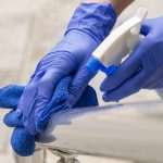 person-disinfecting-hand-rail-with-cleaning-solution